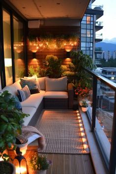 an outdoor living area with couches and potted plants on the balcony at night