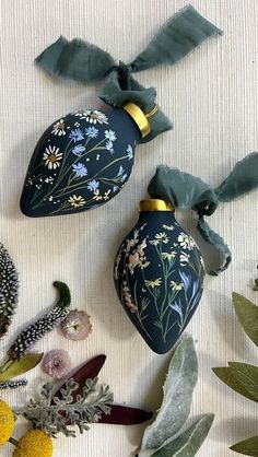 two blue vases sitting on top of a table next to plants and flowers in front of them