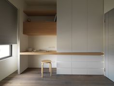 an empty room with white cabinets and a stool next to it on a wooden floor