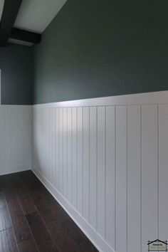 an empty room with green walls and white paneling