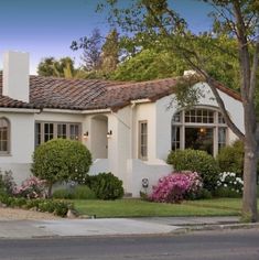 a white house with flowers and trees around it