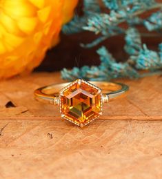 an orange ring sitting on top of a piece of wood next to some yellow flowers