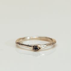 a silver ring with a black diamond in it on a white surface, close up