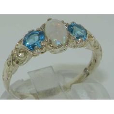 "This is a stunning 14K White Gold Victorian Inspired Trilogy Ring handset with a centre oval cut 6x4 mm (0.24\" x 0.16\") natural Australian Opal and two Brilliant cut 4mm (0.16\") vibrant natural Blue Topaz. The Opal weighs  0.33ct, and the Blue Topaz stones weigh a total of 0.64ct **Overall Dimensions of the ring** Total Height off the finger 3mm Width E to W 14mm Length N to S 7mm All of our jewellery is fully tested and hallmarked by the London, Birmingham or Dublin Assay Office giving you Trilogy Engagement Ring, Blue Topaz Engagement Ring, Trilogy Ring, Topaz Engagement Ring, Vintage Style Rings, Blue Topaz Stone, Australian Opal, Natural Opal, Pink Tourmaline