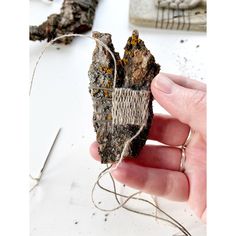 a person holding up a piece of wood that has been cut in half and tied together