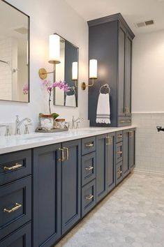 a large bathroom with two sinks, mirrors and lights on the wall above them is shown