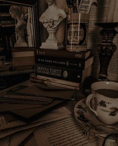 a stack of books sitting on top of a table next to a cup and saucer