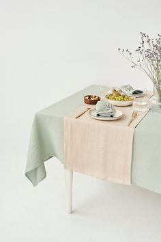 a table topped with plates and bowls of food next to a vase filled with flowers