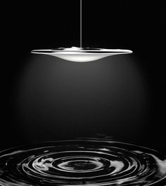 a black and white photo of a light hanging from a ceiling fixture in a dark room