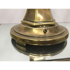 an antique brass and black clock on glass table top with reflection in the mirror behind it