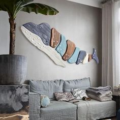 a living room filled with furniture and a painting on the wall next to a potted plant