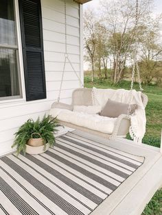 a white porch swing sitting on top of a black and white striped rug