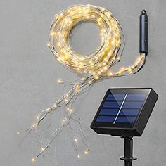 a solar powered string light next to an external charger on a gray background with a black phone