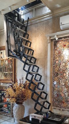 a spiral staircase in a living room next to a vase with flowers on the table