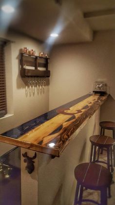 a wooden bar top sitting under a window next to two stools and a shelf