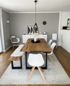 a dining room table with white chairs and a rug on the floor in front of it