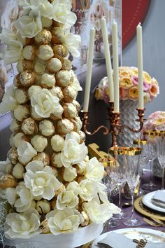 there is a very tall cake decorated with flowers and chocolates on the table in front of candles