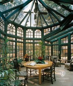 the inside of a green house with lots of windows and plants on the table in front of it