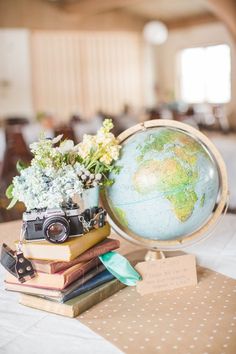 a table topped with books and a small globe on top of each other next to a camera