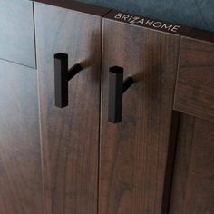 a wooden cabinet with two black handles on it's doors and the name brazhome