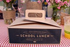 a lunch box sitting on top of a checkered tablecloth covered table with pink flowers