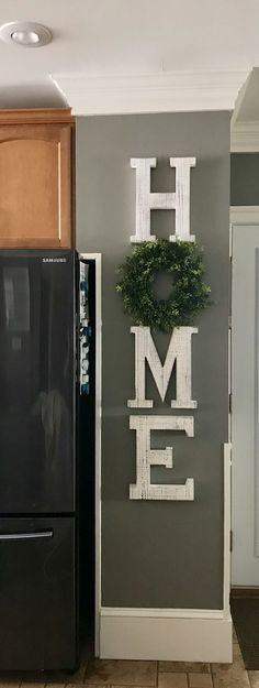 a black refrigerator freezer sitting in a kitchen next to a wooden sign that says home