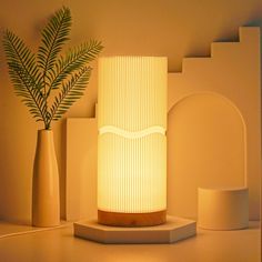 a white lamp sitting on top of a table next to vases and a plant