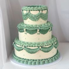 a three tiered green and white cake with ruffles on the bottom layer