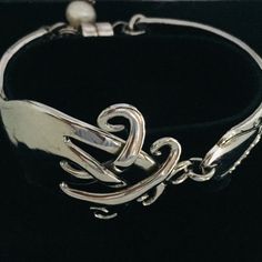 a close up of a silver bracelet on a black background