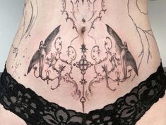 a woman's stomach with tattoos on it and an intricate lace garter around the waist