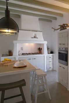 a kitchen with white cabinets and an island in the middle is lit by two pendant lights