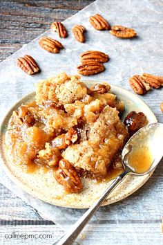 a plate filled with pecans and some oatmeal next to a spoon