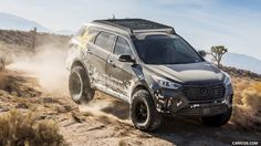 an suv driving down a dirt road in the desert