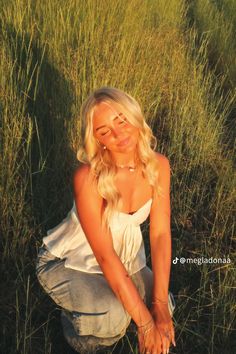 a woman kneeling down in the grass with her hands on her knees and eyes closed