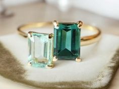 two green and white stones sitting on top of each other in gold ring settings,