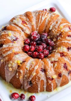 a cranberry orange bundt cake on a white platter with fresh cranberries