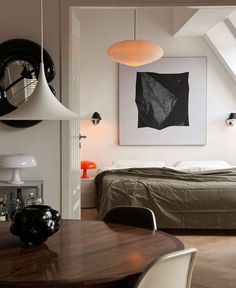 an attic bedroom with white walls and wood flooring is furnished with modern lighting fixtures