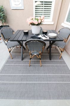 a black table with four chairs and a potted plant on it in front of a house