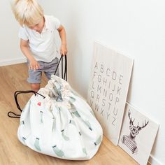 a little boy standing next to a bag on the floor