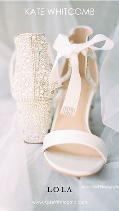 a pair of white high heel shoes sitting on top of a bed next to a bride's veil