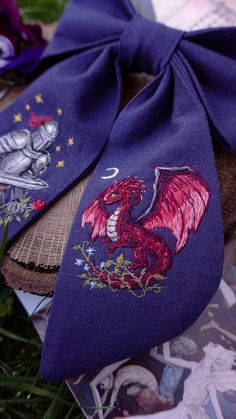 a purple tie with a red dragon on it sitting next to some pictures and flowers