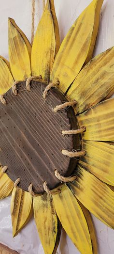 a sunflower shaped object is hanging on a wall with twine strings and rope