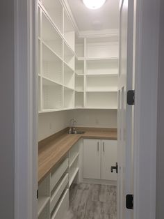 an empty walk in closet with white cabinets and wood counter tops on one side, open shelves to the other