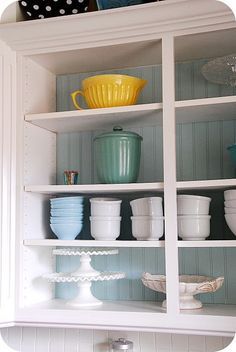 the shelves in the kitchen are filled with dishes and bowls, including one yellow bowl