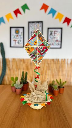 a colorful kite sitting on top of a wooden table next to potted cacti