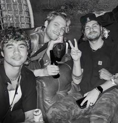 three men sitting on a couch holding wine glasses in their hands and smiling at the camera