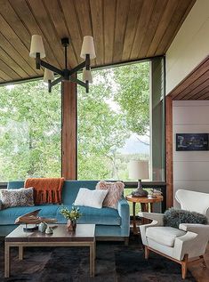 a living room filled with furniture under a large window next to a wooden floor and ceiling