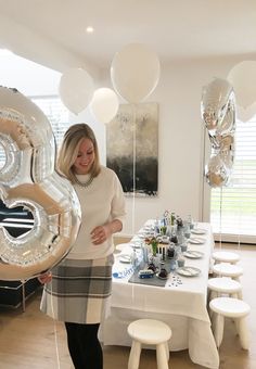 a woman standing in front of a table with balloons