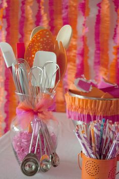 there are many utensils in the cup on the table with pink and orange streamers