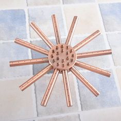 a clock made out of copper sticks on a tiled floor